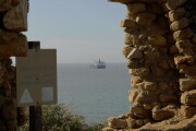 View through the remains of ancient wall, sea tanker at parking