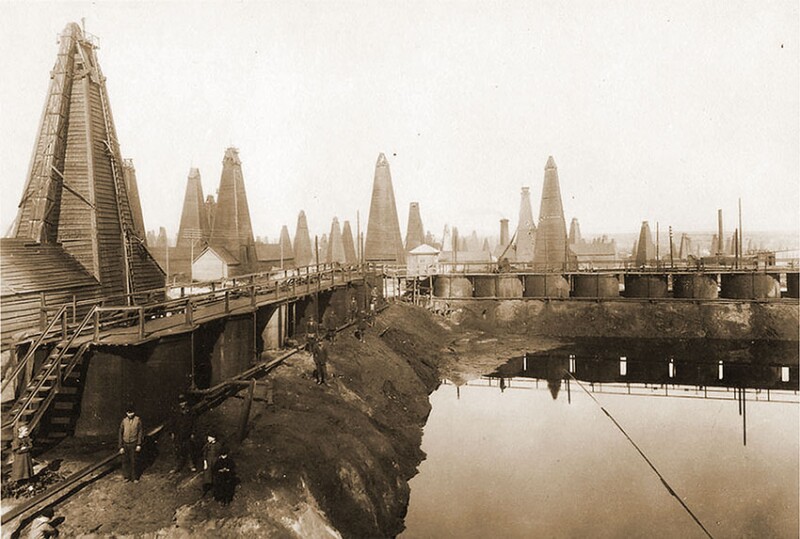 Cisterns reflect off crude oil and waste products captured in a pit adjacent to production wells in the Balakhani oil field in Baku, 1900–1917.
