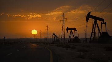 Oil wells and power lines on the side of the highway.