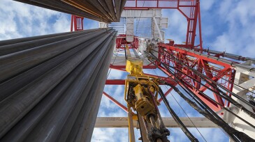 Drilling rig view with Top Drive, many pipes, sky bottom up view in sunny weather in Siberia