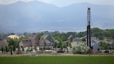 Natural gas drill rig with homes and Colorado Rocky mountains