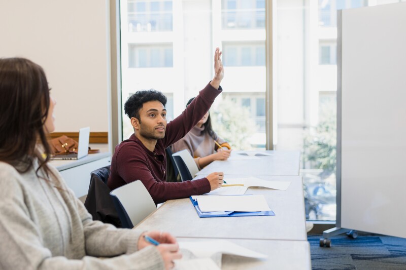 Young man eagerly raises hand in class