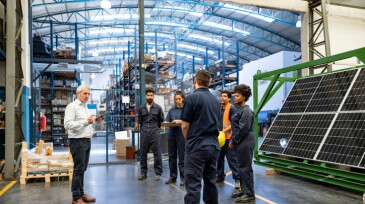 Manager talking to a group of employees at a solar panel factory