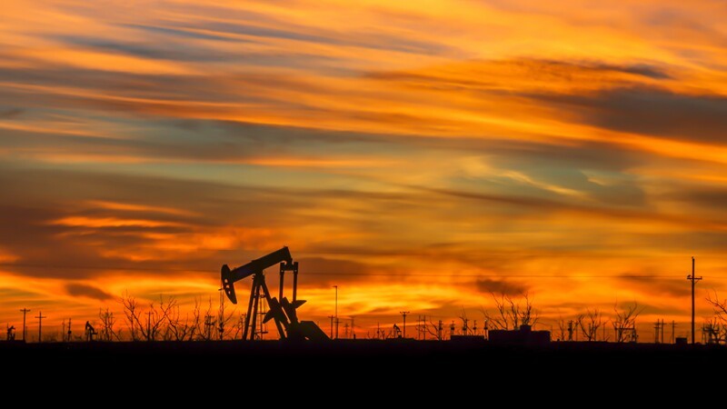 The natural beauty of a vibrant sunrise shines through the industries silhouette of the west Texas oil fields.