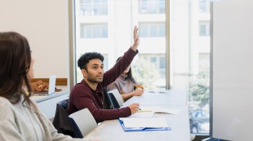 Young man eagerly raises hand in class