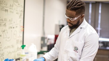 A student works in a hydraulic fracture conductivity laboratory.