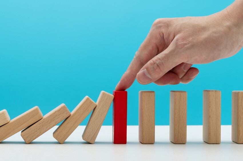 Man hand stopping the dominos falling