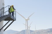 Workers standing on wind turbine in rural landscape