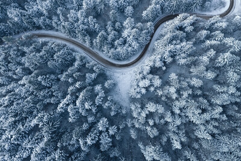 Road leading through snowcapped winter forest. Aerial view.