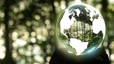 Focus on taking care of nature and the climate shown with a globe around  a crystal ball with nature reflected and inside the ball