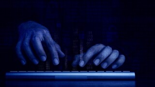 Cyberattack and internet crime, hacking and malware concepts. Digital binary code data numbers and secure lock icons on hacker' hands working with keyboard computer on dark blue tone background.