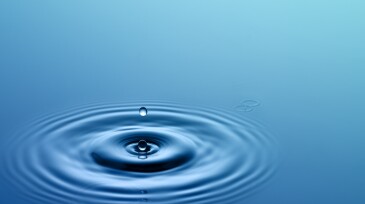 Single drop of water hitting a larger body of water